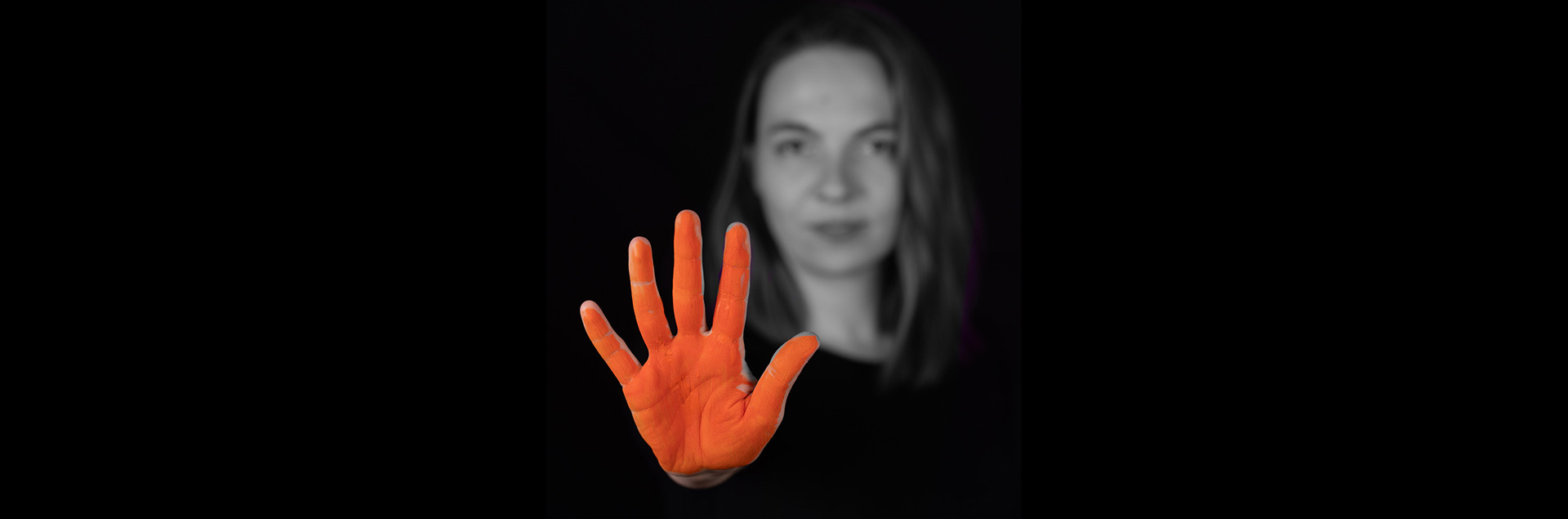 Das Bild zeigt eine FLINTA*-Person. Im Vordergrund steht ihre rot angemalte Hand, die ausgespreizt „Stopp!” bedeutet.